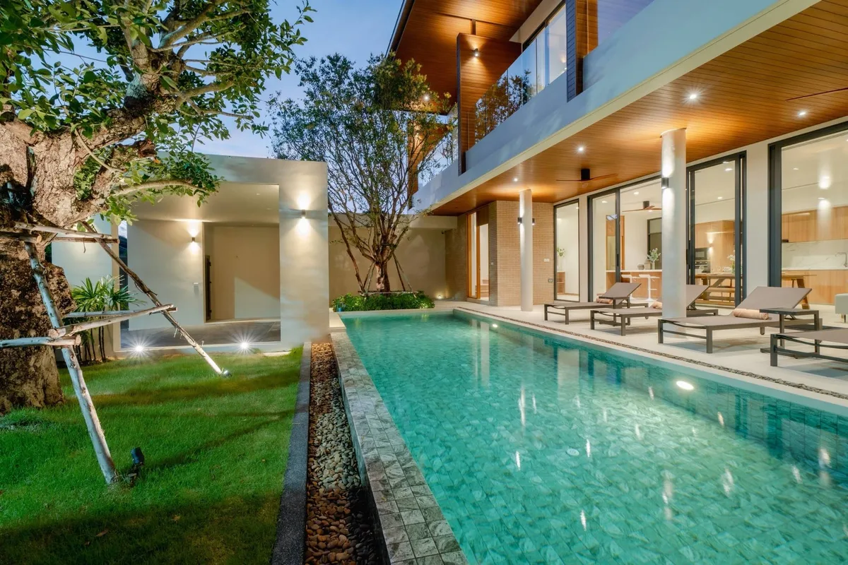 A modern villa and lap pool photographed at dusk with the interior lit.